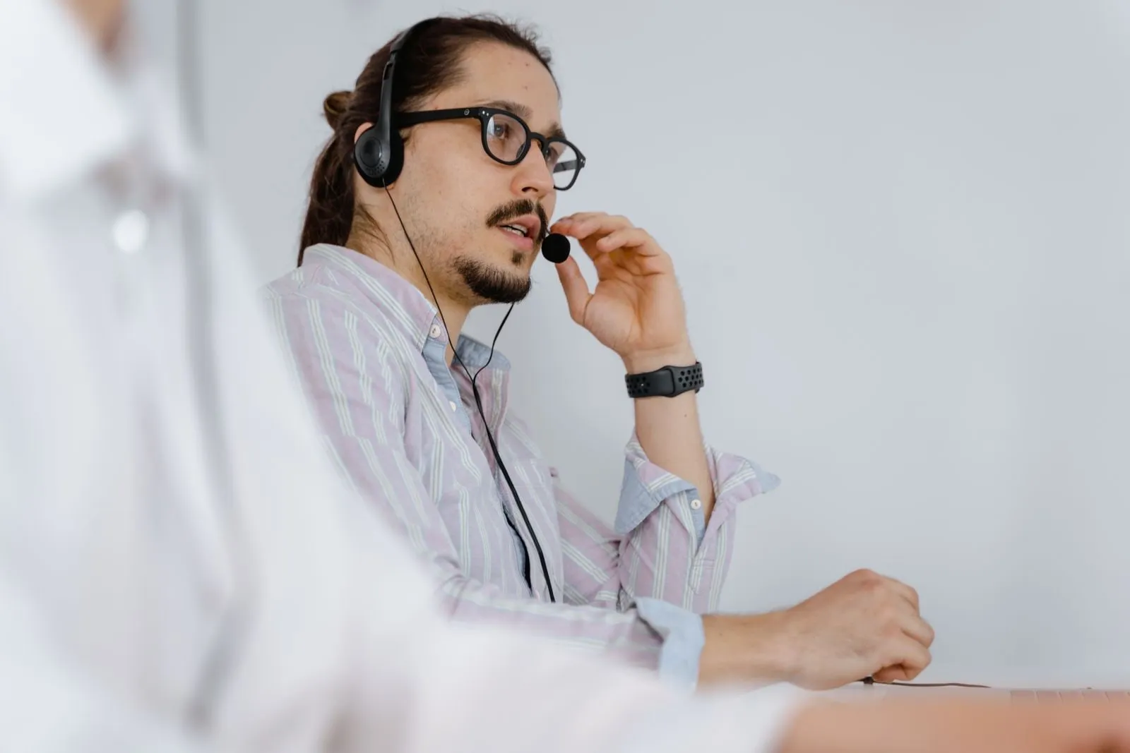 Mann mit Büro-Headset bei einem Telefonat am Arbeitsplatz
